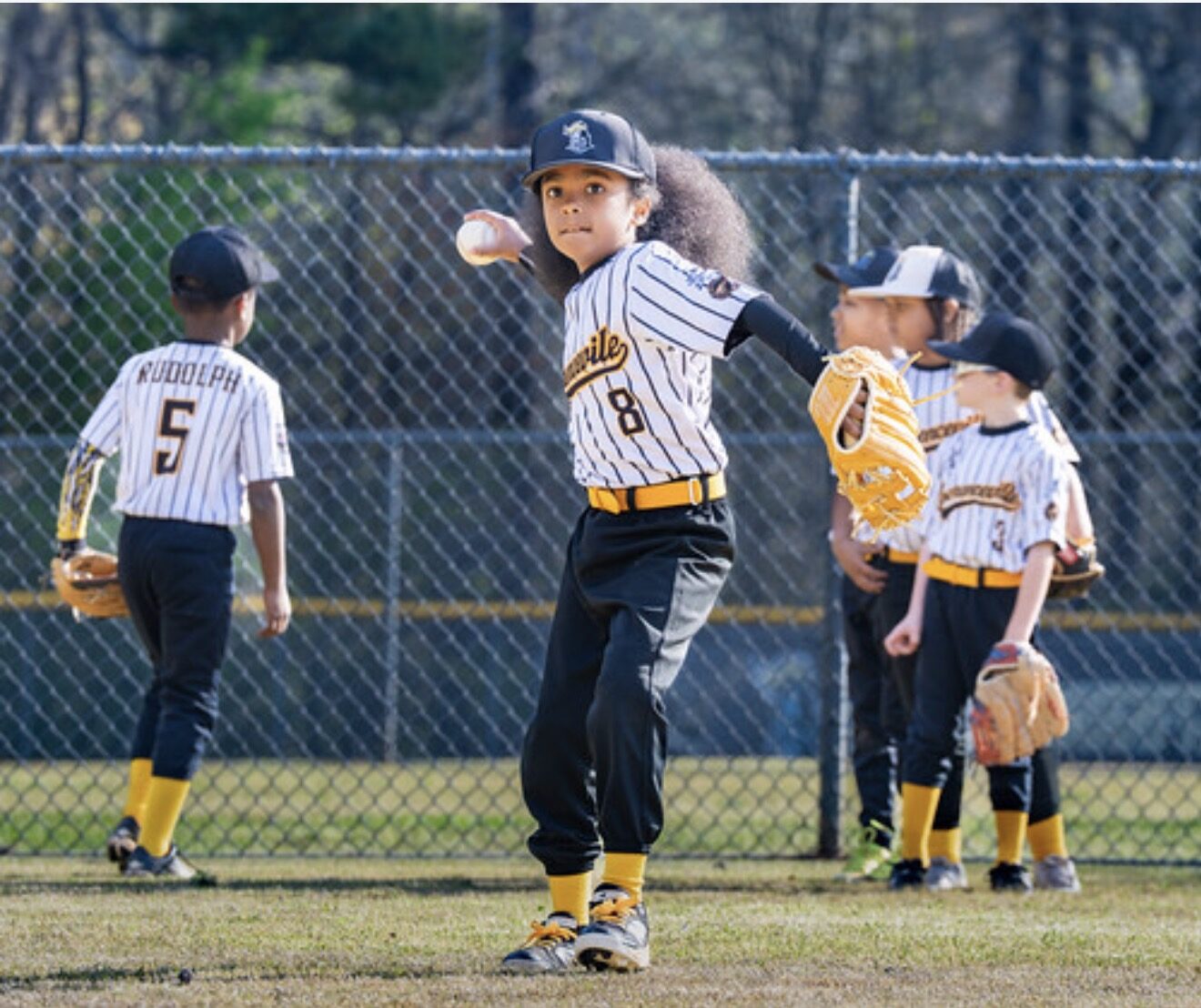 Noah throwing, glove out, teammates on the line